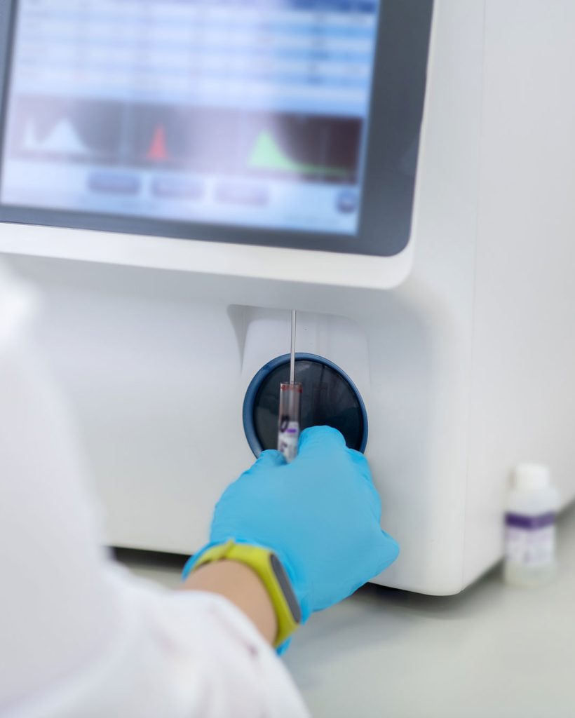 Technicien insérant un échantillon dans une machine d’analyse biomédicale